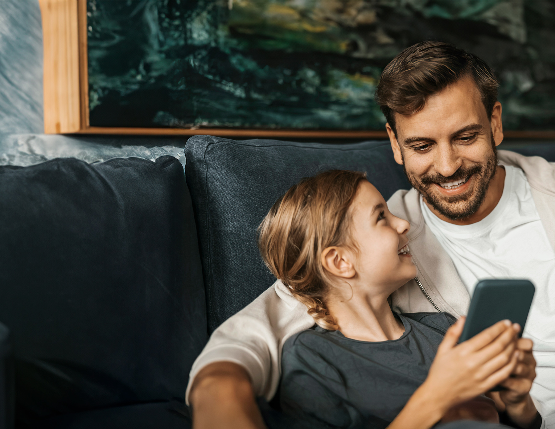Pappa och dotter kollar i en telefon