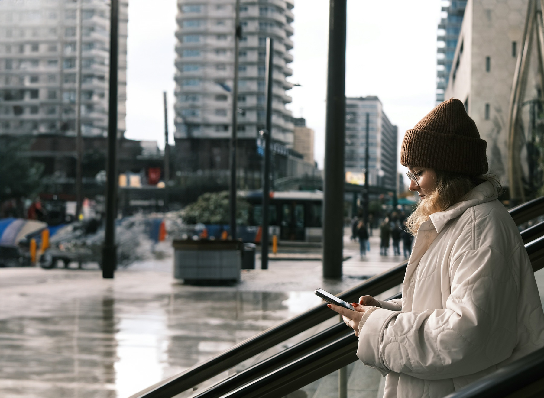 Kvinna i rulltrappa som kollar i sin telefon